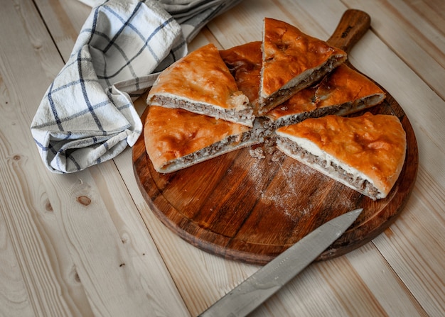 Traditional Ossetian meat pies with beef, on a wooden table. Rustic style, close up, selective focus