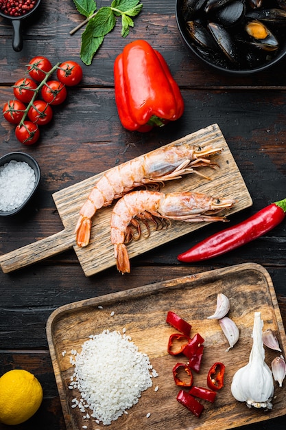 Traditional paella valenciana raw ingredients with shrimps, mussel, rice and squid over dark rustic wooden background