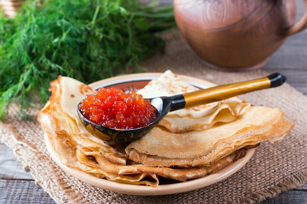 Traditional pancakes with red caviar on wooden rustic background