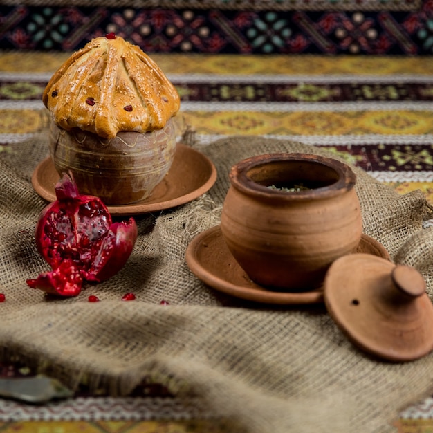 Traditional pilaf in clay pots on patterned cloths background