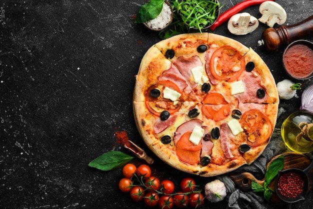 Traditional pizza with bacon tomatoes and cheese On a black stone background Free space for text