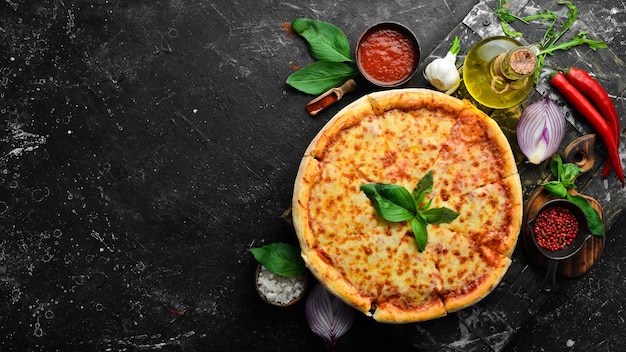 Traditional pizza with cheese and tomato sauce. On a black stone background. Free space for text.