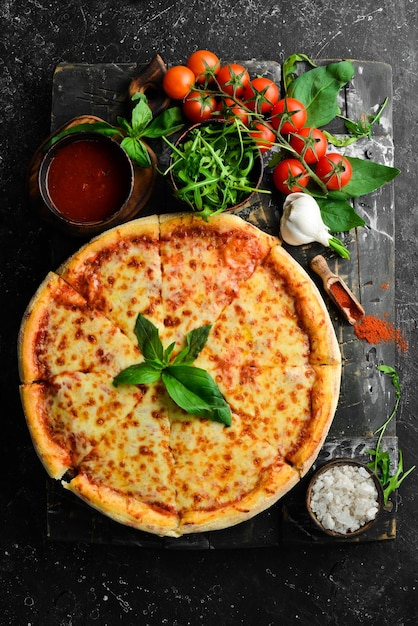 Traditional pizza with cheese and tomato sauce on a black stone\
background free space for text