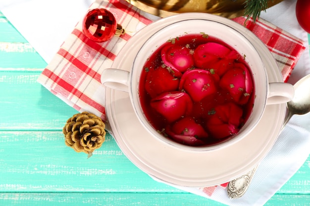 Traditional polish clear red borscht with dumplings on wooden background