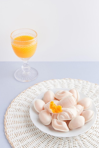 Traditional portuguese egg yolk sweets Ovos Moles de Aveiro with orange juice on blue background Confectionery shop