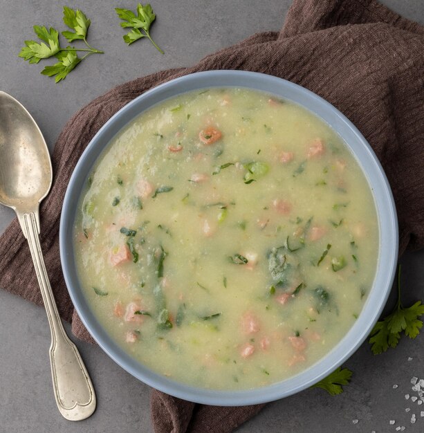 Traditional portuguese green soup with potato green cabbage and sausage in a bowl over stone background