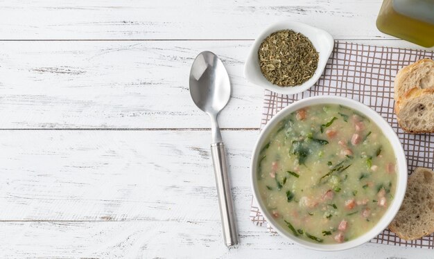 Traditional portuguese green soup with potato green cabbage and sausage in a bowl with bread and copy space