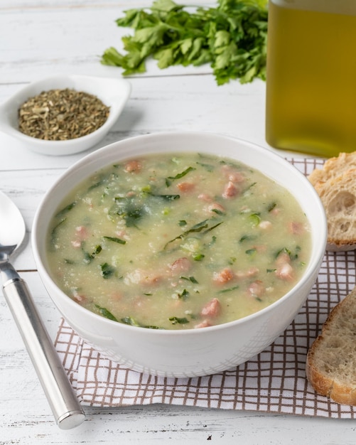 Traditional portuguese green soup with potato green cabbage and sausage in a bowl with bread