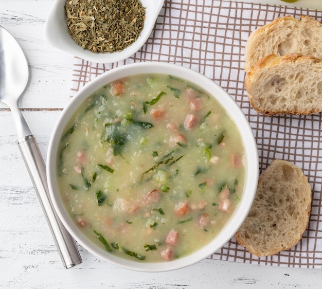 Traditional portuguese green soup with potato green cabbage and sausage in a bowl with bread