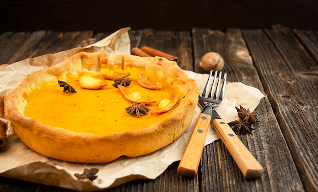 Traditional pumpkin pie on a wooden table. Side view.