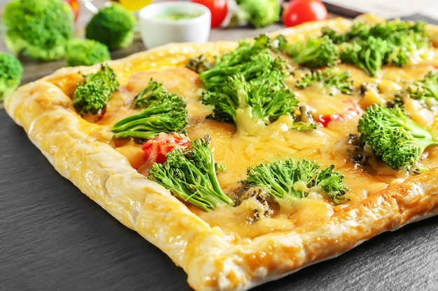 Traditional quiche with broccoli and cheese on slate plate close up