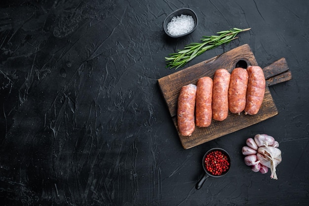 Traditional raw pork sausages flat lay with space for text on black background