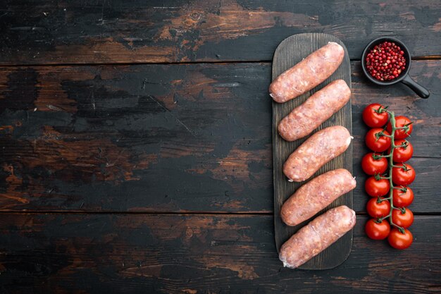 Traditional raw pork sausages, flat lay with space for text, on old dark wooden background