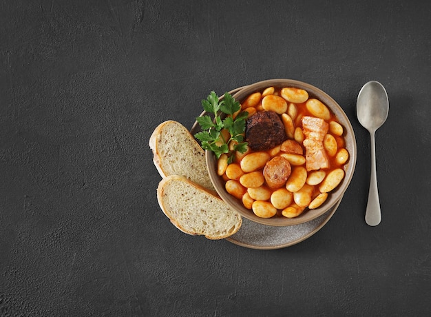 Traditional recipe of beans with chorizo and blood sausage of Fabada Asturiana on a dark table Top view copy space