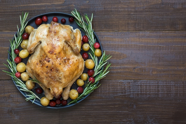 Traditional roasted chicken with spices and rosemary on wooden table. T