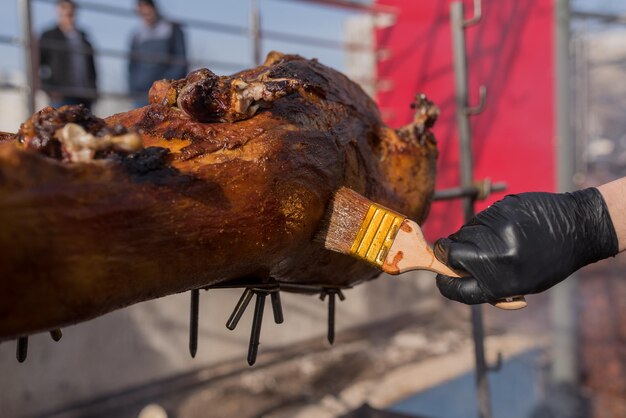 Traditional roasted shank ham cooking on charcoal spit roaster