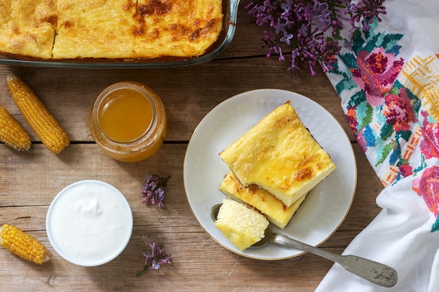 Tradizionale casseruola di ricotta rumena o moldava con farina di mais, servita con miele e panna acida.