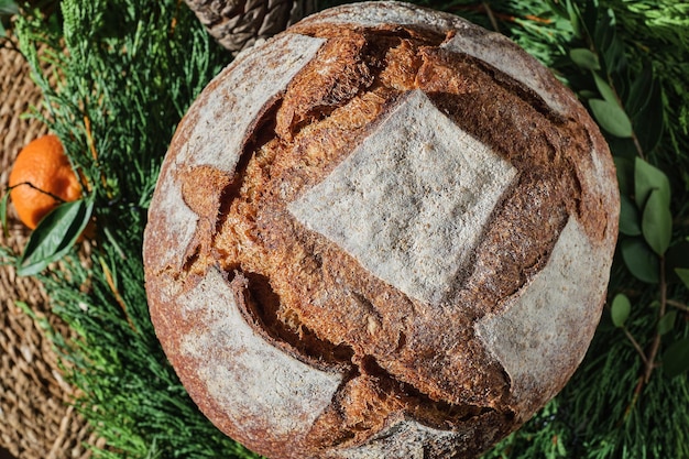 Traditional round bread on a christmas wreath top view sale of\
handicraft bread for the new year holidays