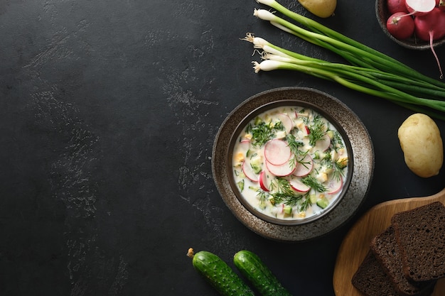 Traditional russian cold okroshka soup with kefir on a black background