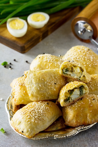 Traditional Russian cuisine Pies egg and green onions on light stone table