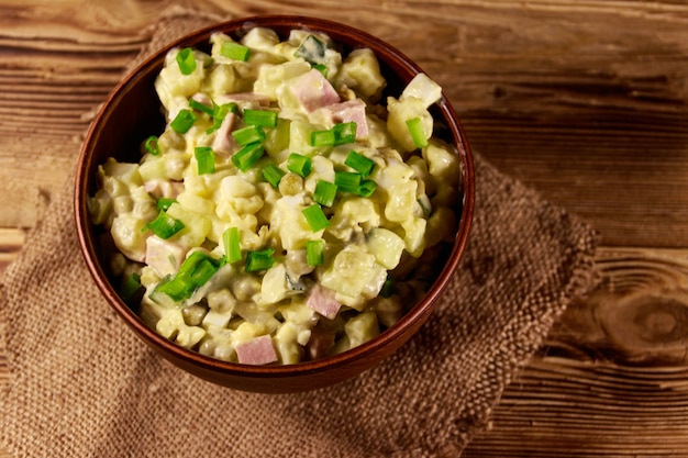 Traditional Russian festive salad Olivier on wooden table