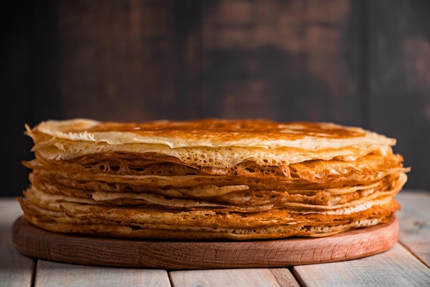 Traditional Russian food thin pancakes A stack of crepes on a dark brown wooden background