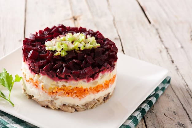 Traditional Russian herring salad on wooden table