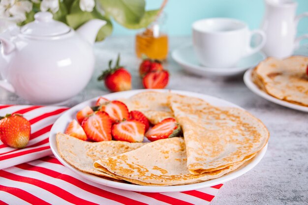 Traditional russian homemade thin pancakes blini crepes with fresh ripe strawberries
