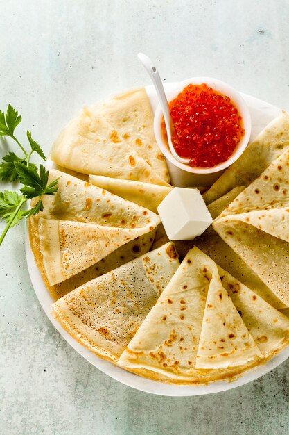 Traditional Russian pancakes with red caviar and butter on the table