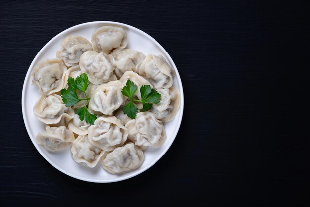 Traditional russian pelmeni ravioli dumplings with meat on black background Top view Copy space