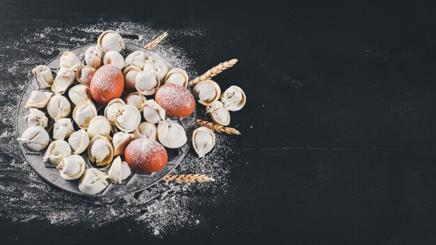 Traditional russian pelmeni ravioli dumplings with meat on black concrete background Top view Copyspace