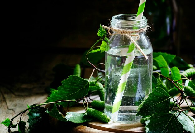 Traditional Russian refreshing drink birch juice in a small bottle vintage dark wood background selective focus