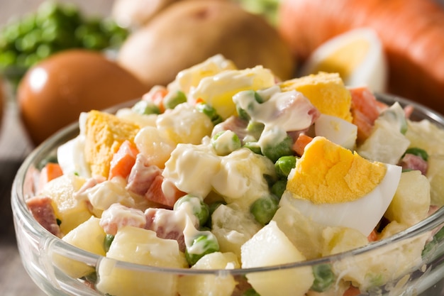 Traditional Russian salad in bowl Olivier salad on wooden table close up