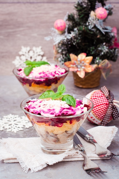 Traditional Russian salad, herring under a fur coat in bowls in Christmas decorations on the table. Russian kitchen