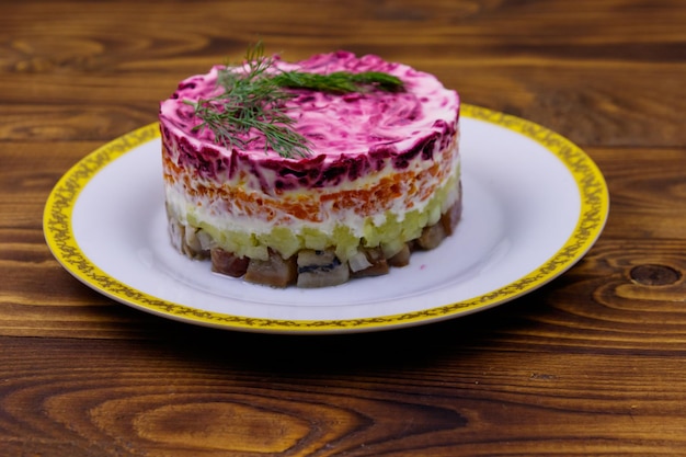 Traditional russian salad Herring under a fur coat shuba on wooden table Layered salad with herring beets carrots onions potatoes and eggs