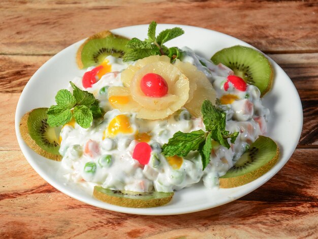 Traditional russian salad quotolivierquot from boiled\
vegetables and sausage with mayonnaise in bowl served over a rustic\
wooden background selective focus