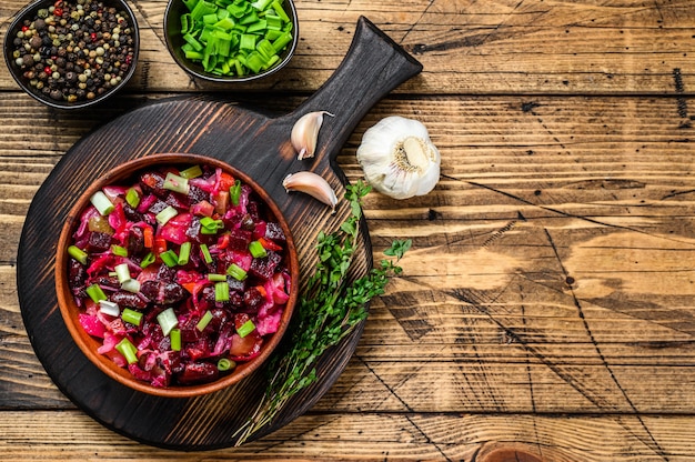 ボイルした野菜、ボウルにキュウリのピクルスを添えた伝統的なロシア風サラダ ビネグレット。木製の背景。上面図。スペースをコピーします。