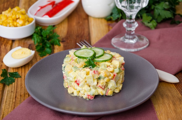 Traditional Russian salad with crab sticks, fresh cucumbers, corn and boiled eggs