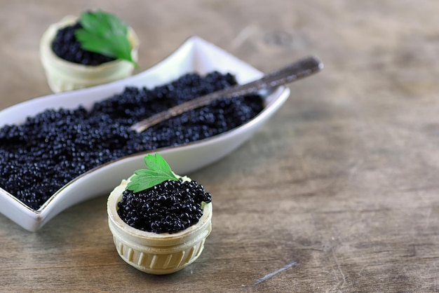 Spuntino russo tradizionale caviale nero su fondo di legno