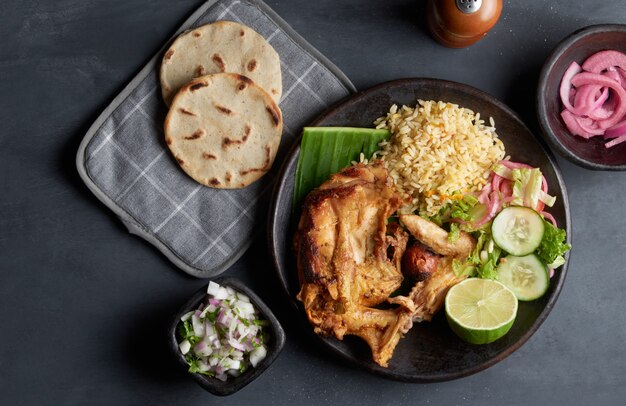 Traditional salvadoran dish roasted hen served with rice, lemon, onion and corn tortillas, latin america food