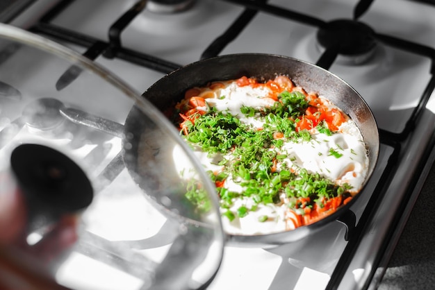 Cibo shakshuka tradizionale uova fritte spezie in padella sul fornello a gas in cucina