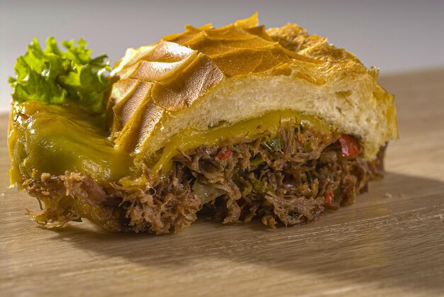 Traditional shredded roast beef sandwich with melted cheese on wheat bread and lettuce, tomato and herb mayonnaise.