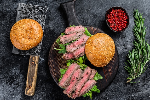 Traditional sliced cold cuts roast beef burger with onion, gherkin, arugula and spinach