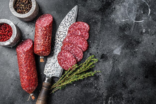 Traditional smoked salami cured sausage on kitchen table. black\
background. top view. copy space.