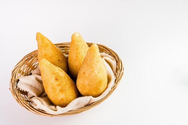 브라질에서 Coxinha로 알려진 전통 스낵 치킨 Coxinha는 바구니에 담아 흰색 배경 선택적 포커스를 제공합니다.