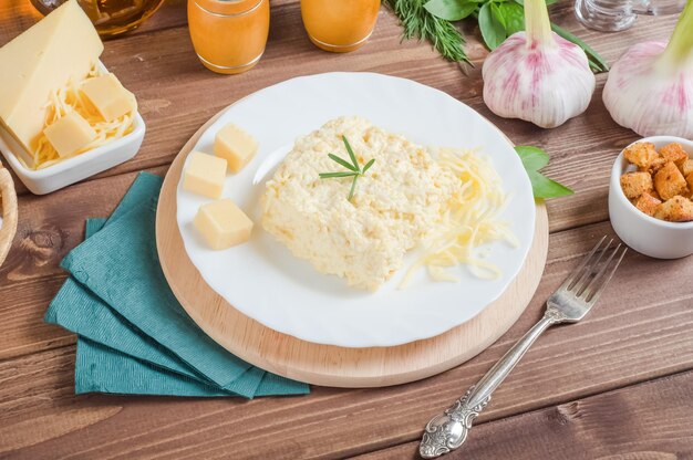 Antipasto tradizionale di formaggio a pasta molle con aglio e maionese su un piatto bianco su fondo di legno