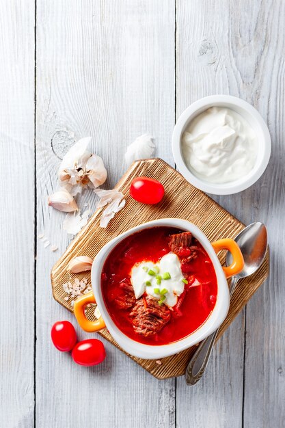 Traditional soup of Russian and Ukrainian cuisine borsch. Meat soup with beets in an orange bowl. Top view.