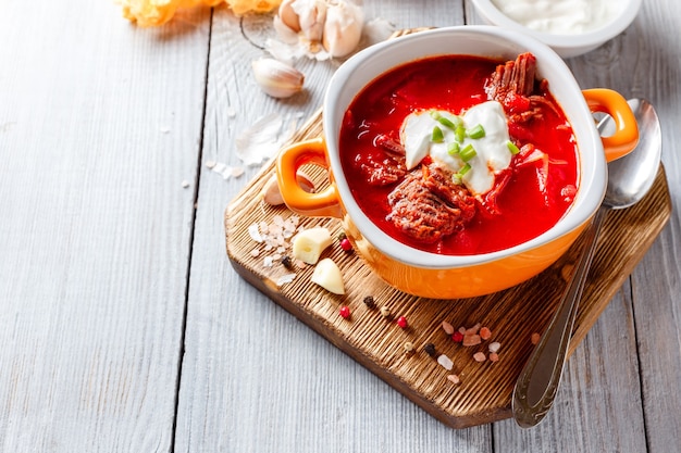Traditional soup of Russian and Ukrainian cuisine borsch. Meat soup with beets in an orange bowl.