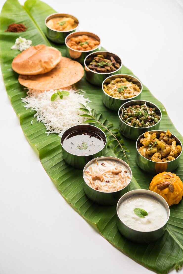 Photo 伝統的な南インド料理または大きなバナナの葉で提供される料理、フードプラッターまたは完全なターリー。セレクティブフォーカス