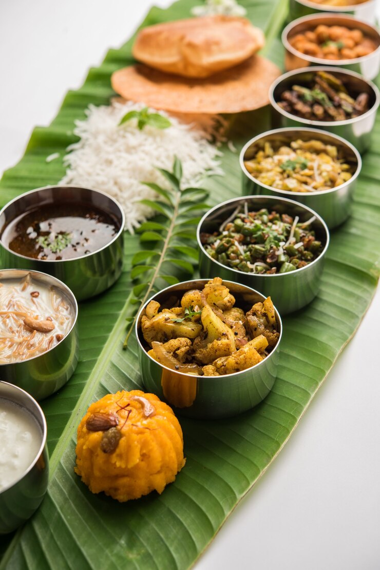 Photo 伝統的な南インド料理または大きなバナナの葉で提供される料理、フードプラッターまたは完全なターリー。セレクティブフォーカス